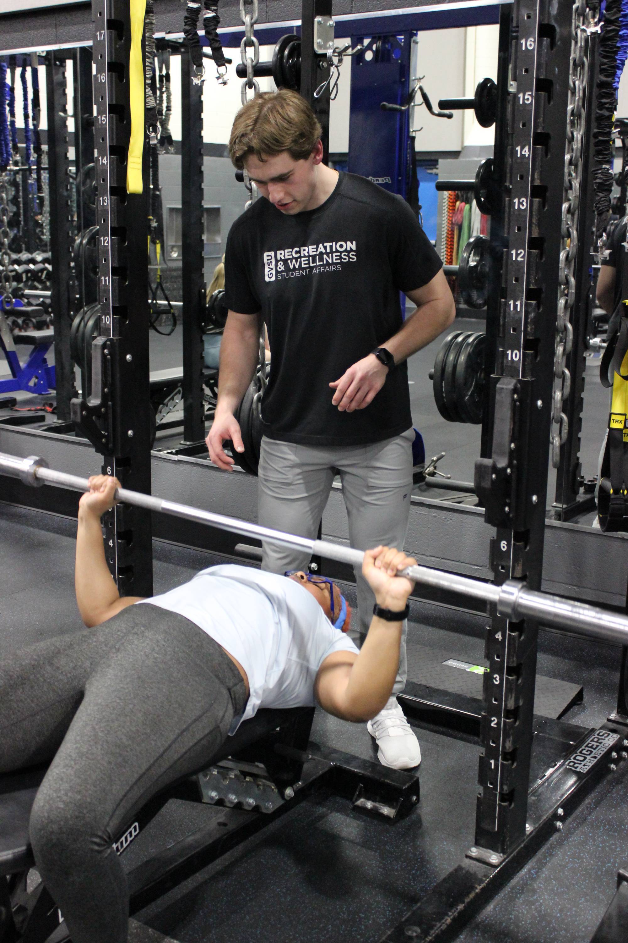 Personal trainer spotting a client with a bench press.
